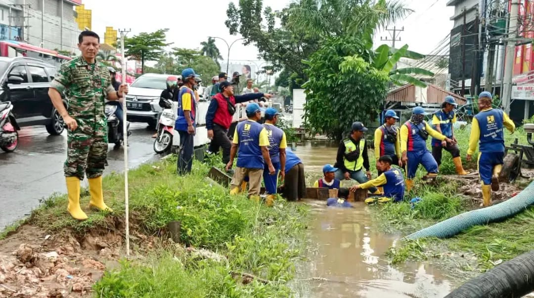 Anggota TNI dari Kodim 0418/Palembang membantu warga menanggulangi banjir akibat hujan deras di kota Palembang, Jumat (09/12/2022)