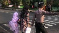 Personel Polres Ciamis saat membantu anak sekolah menyeberang