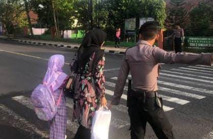 Personel Polres Ciamis saat membantu anak sekolah menyeberang
