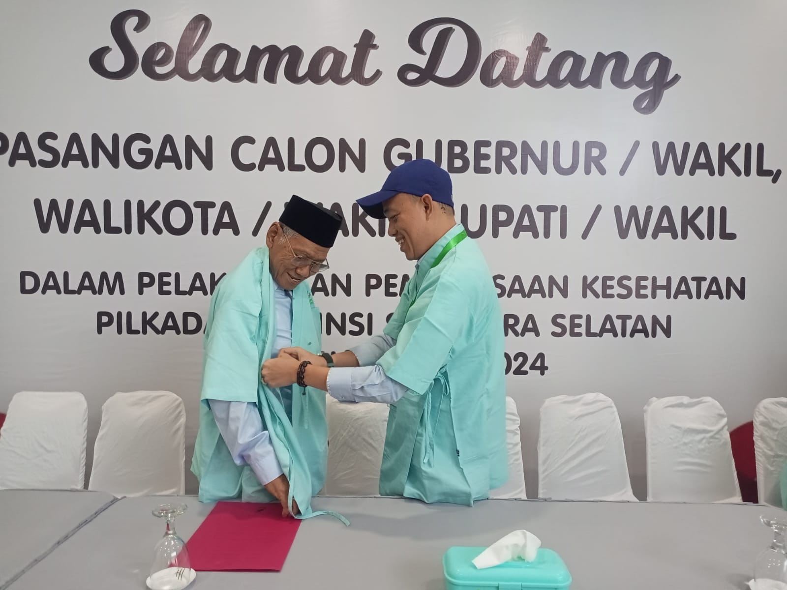 Bakal calon (balon) Wabup Banyuasin Alfi N Rustam membantu memperbaiki baju balon Bupati Banyuasin Slamet Somosentono, saat mengikuti serangkaian tes kesehatan di RSMH Palembang (Dok. Humas Tim Pemenangan Slamet-Alfi)