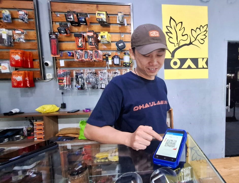 Owner OAK Outdoor Store Peri Arif memamerkan salah satu transaksi nontunai pakai barcode QRIS yang banyak dipilih pelanggannya (Indodaily.co)