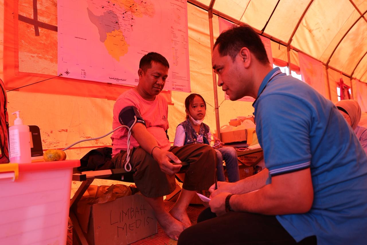 Salah satu warga bersama dengan putrinya memeriksa kesehatan di Posko Pertamina Peduli  'Melayani Sepenuh Hati', di Simpang Kantor Disdukcapil Aceh Tamiang, Aceh, Kamis, (1/1/2026). Pengobatan gratis disediakan Pertamina Peduli untuk warga yang terdampak bencana banjir dan tanah longsor di Provinsi Aceh (Dok. Pertamina / Indodaily.co)